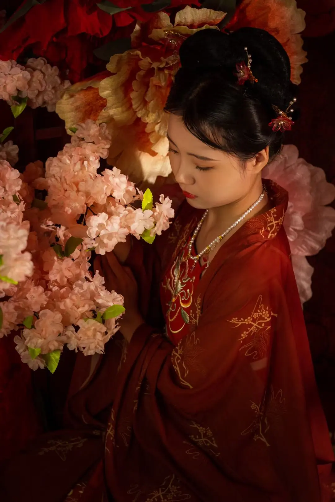 A studio portrait in crimson Hanfu surrounded by flowers
